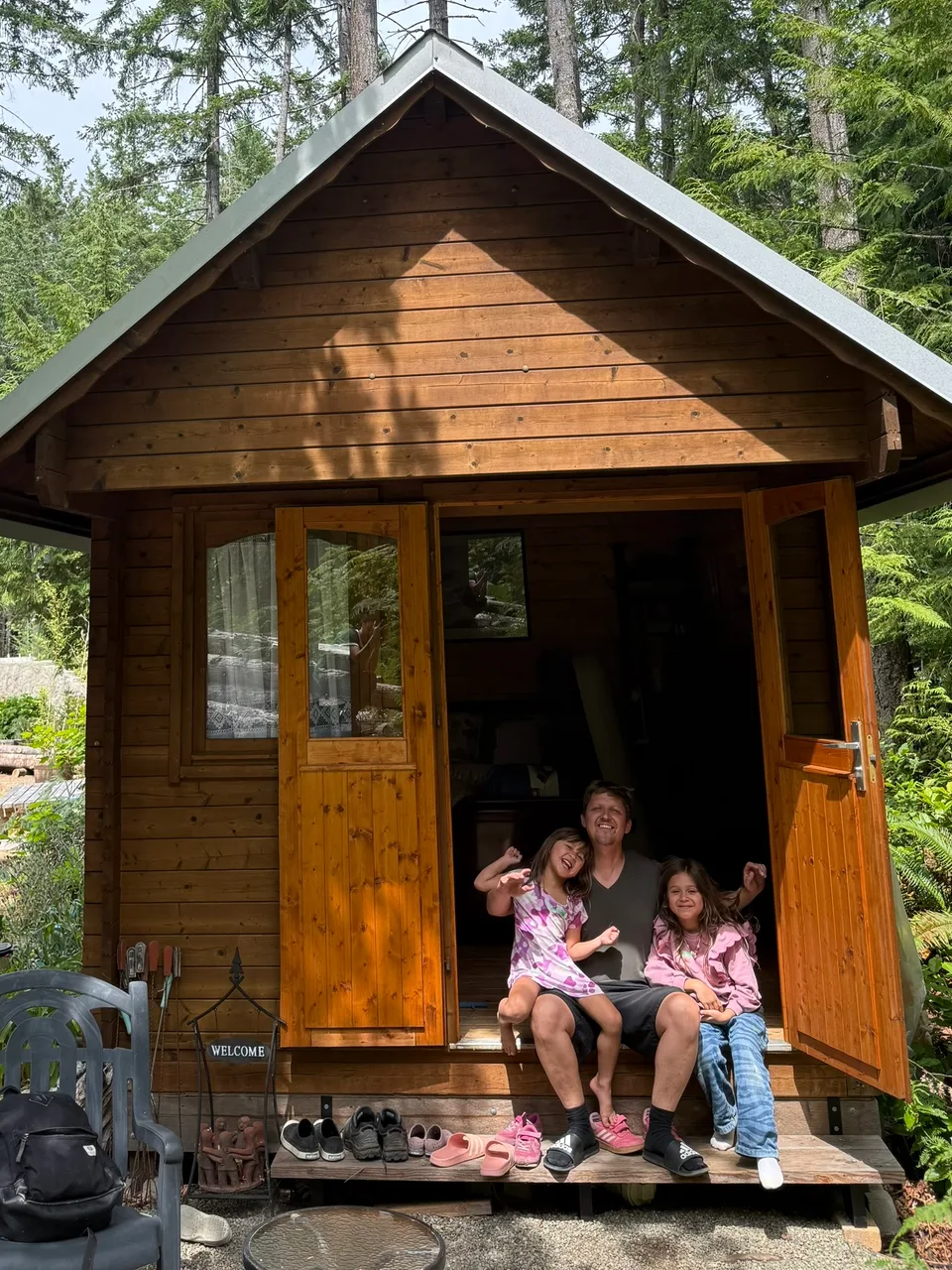 Die beiden Kinder sitzen gemeinsam vor einer kleinen Holzhütte im Grünen