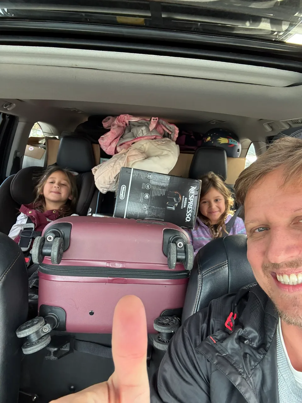 Martin und die Kinder im vollgepackten Auto mit Koffern für die Weiterreise